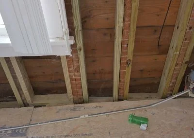 Interior view of wooden beams and brick wall in a residential property, showcasing structural elements relevant to foundation repair by Southern Structural Solutions.
