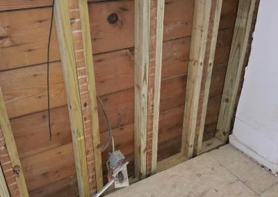 Wooden wall framing with exposed studs and electrical wiring, illustrating foundation repair work by Southern Structural Solutions.