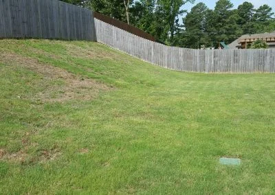 Grassy slope with wooden fence, showcasing a residential yard, relevant to Southern Structural Solutions' foundation repair services.