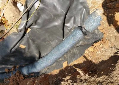 Foundation repair project featuring a blue drainage pipe on black fabric, surrounded by soil and construction materials, illustrating Southern Structural Solutions' expertise in structural services.