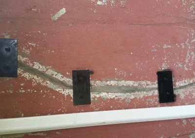 Foundation repair work showcasing wall cracks with structural reinforcement plates installed, illustrating Southern Structural Solutions' expertise in structural solutions.