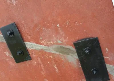 Foundation repair with metal brackets and bolts on a cracked concrete surface, showcasing structural solutions by Southern Structural Solutions.