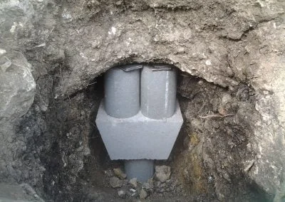 Foundation repair piling installation in excavated soil, showcasing structural support for residential properties.